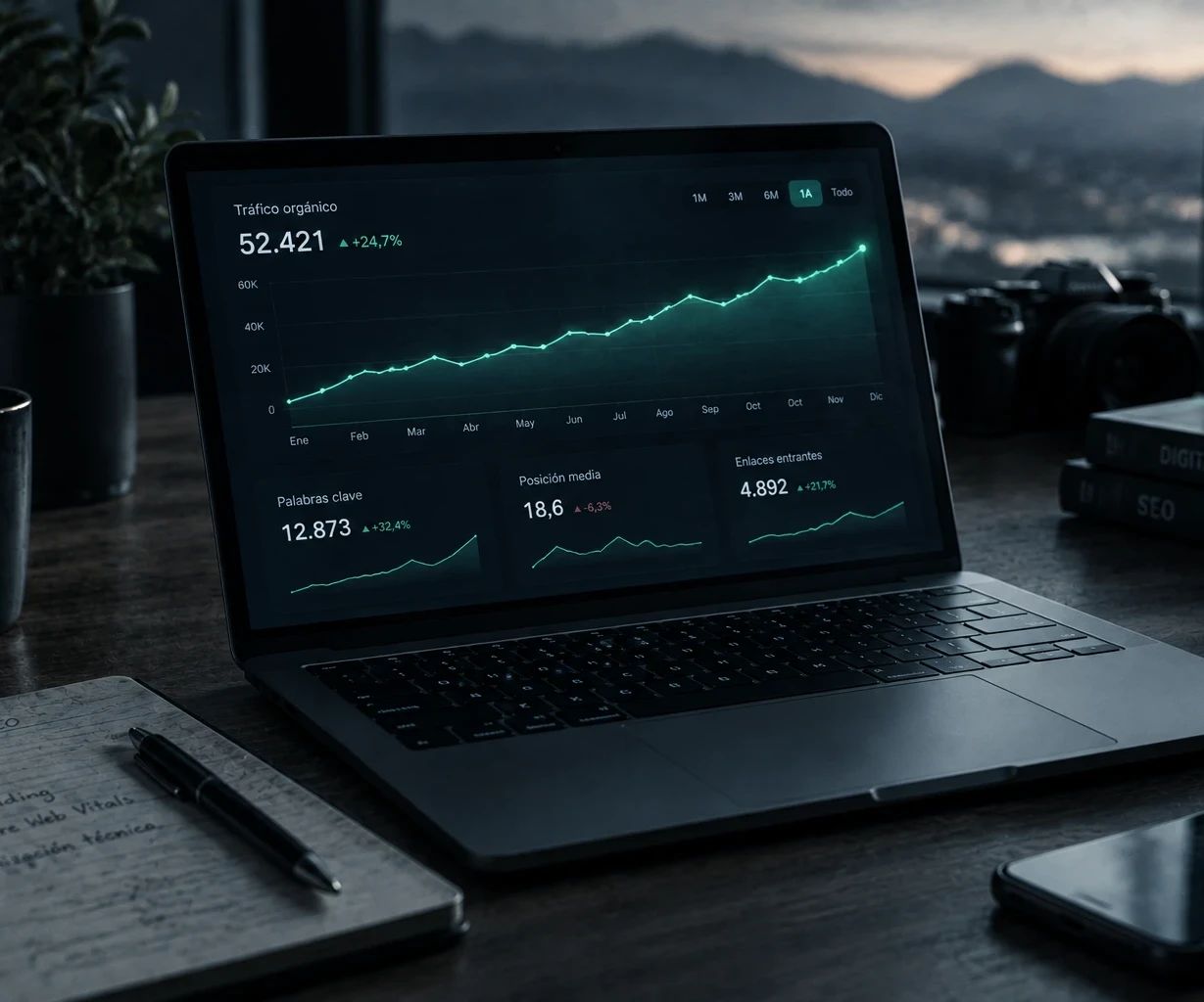 Portátil con un panel de tráfico orgánico en crecimiento sobre una mesa, junto a una libreta con la estrategia SEO